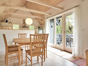 Ein Essbereich mit Holztisch und -stühlen, eine Küche mit Mikrowelle und eine Schiebetür zu einer Terrassenfläche.
