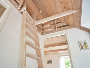 A wooden staircase with a wooden ceiling and a white wall with a framed picture.