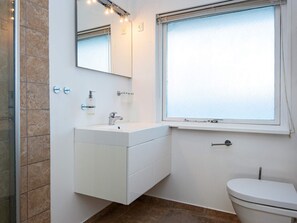 A bathroom with a white vanity, a mirror, a window, and a toilet. - 4 Person Holiday Home in Knebel (Knebel)