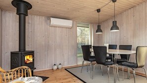 Une pièce chaleureuse avec un poêle à bois, une table à manger avec des chaises et une grande fenêtre.