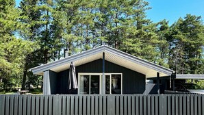 Il s’agit d’un bâtiment d’un seul étage, à l’extérieur sombre, doté d’un patio couvert et d’une clôture en bois à l’avant.