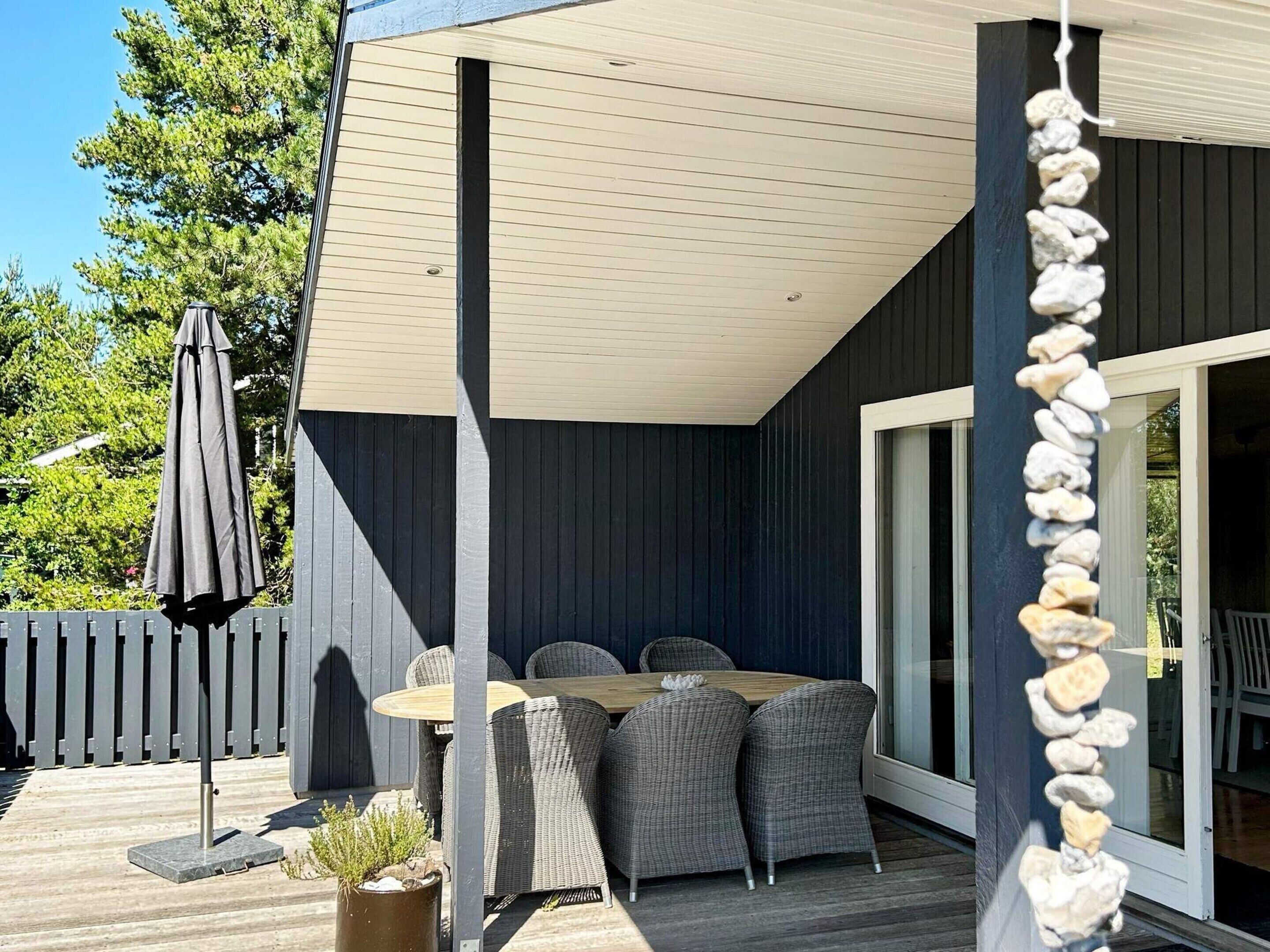 A covered patio area with a table and chairs, a potted plant, and a stone wall decoration.