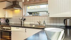 Une cuisine moderne avec une cuisinière en acier inoxydable, un plan de travail noir et une fenêtre au-dessus de l’évier.