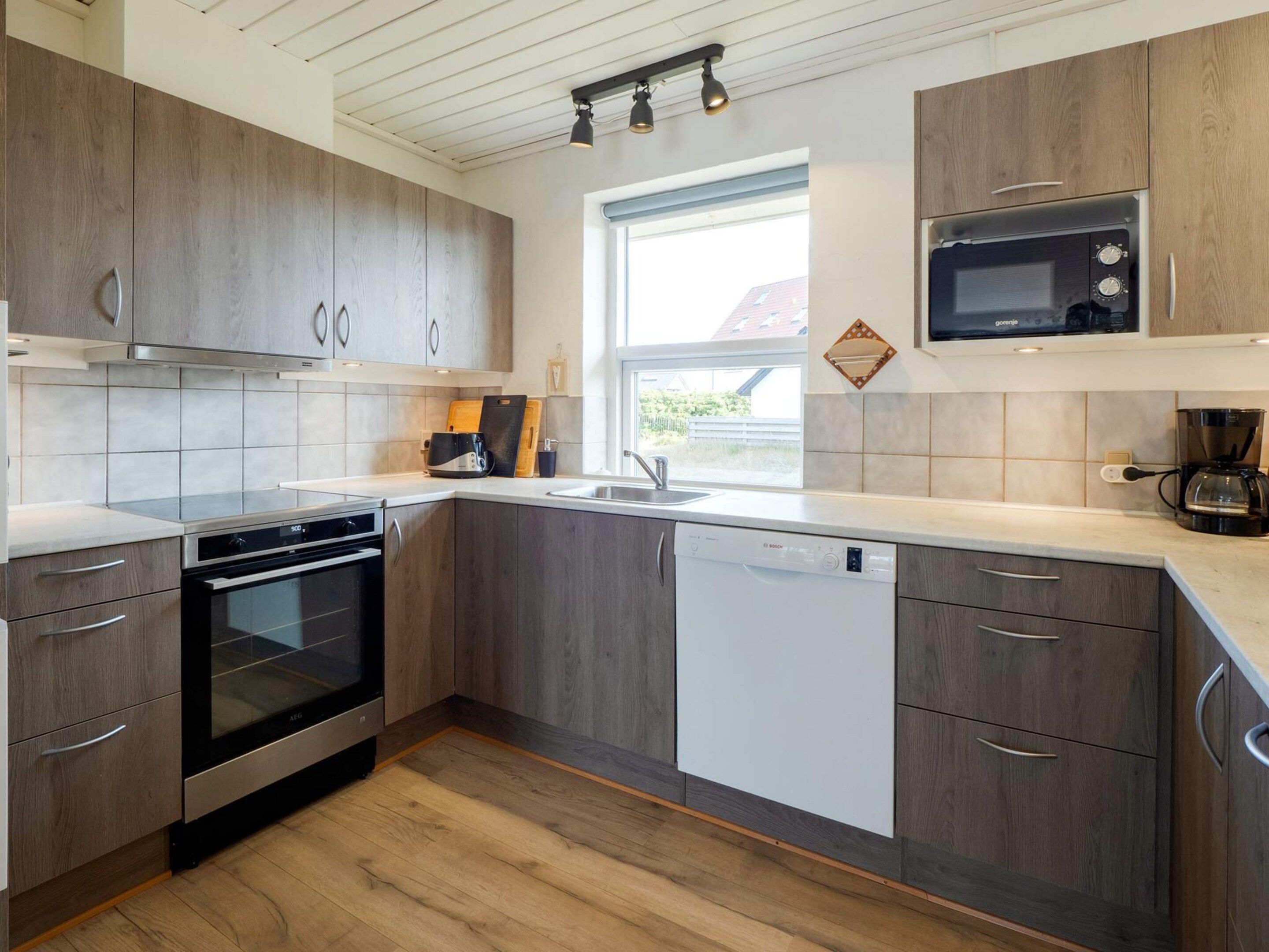 Una cocina moderna con armarios de madera, electrodomésticos de acero inoxidable y un ventanal que proporciona luz natural.