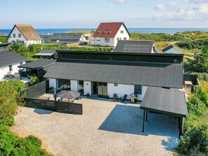 A coastal building with a covered patio, outdoor seating, and a view of the sea.