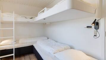Une chambre avec un lit superposé, une échelle, une lampe fixée au mur et une prise de courant.