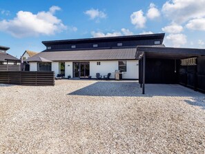 A building with a gravel driveway, a covered outdoor seating area, and a garage.