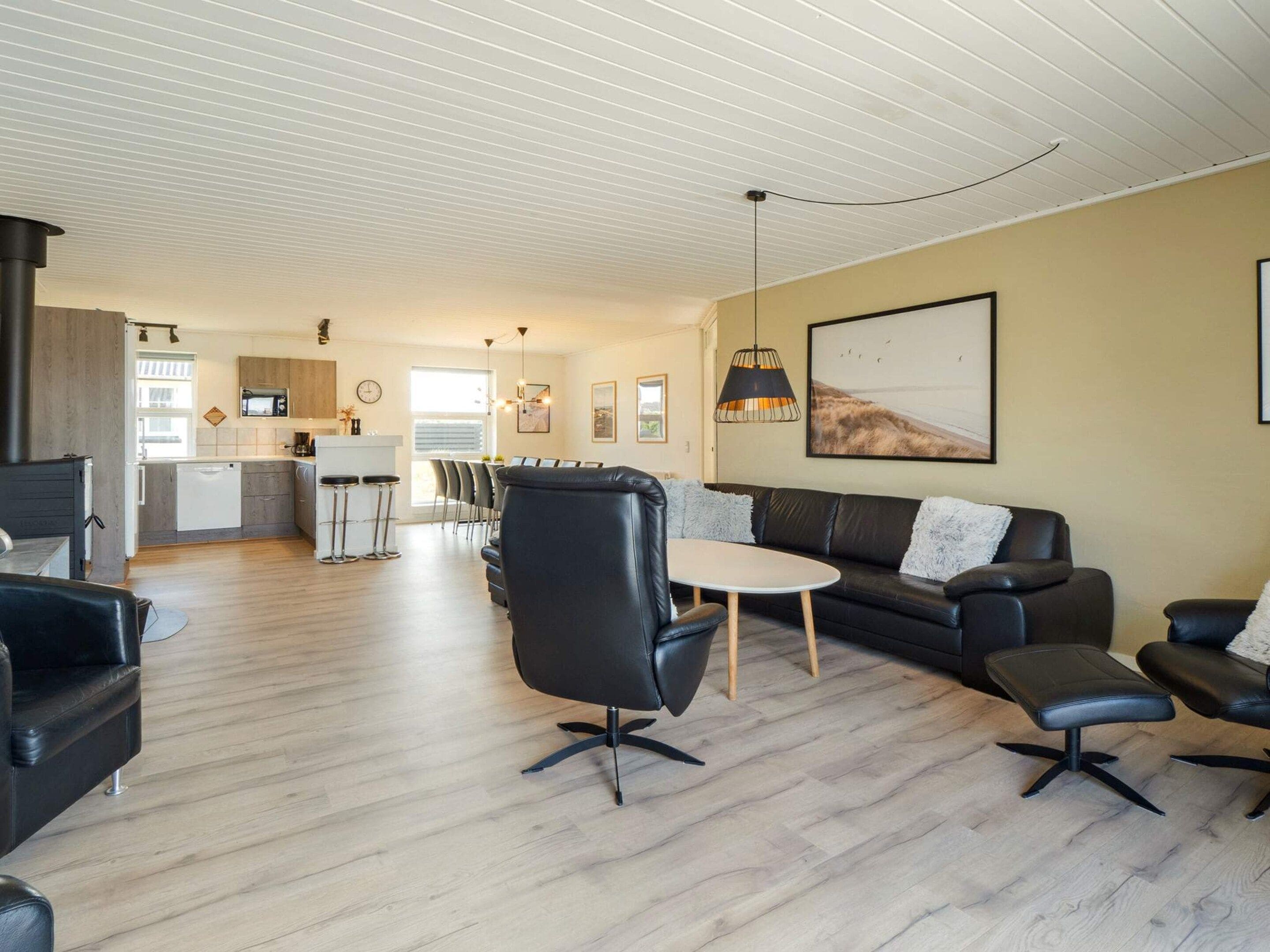 A modern living room with a sofa, chairs, a dining table, and a kitchen in the background.