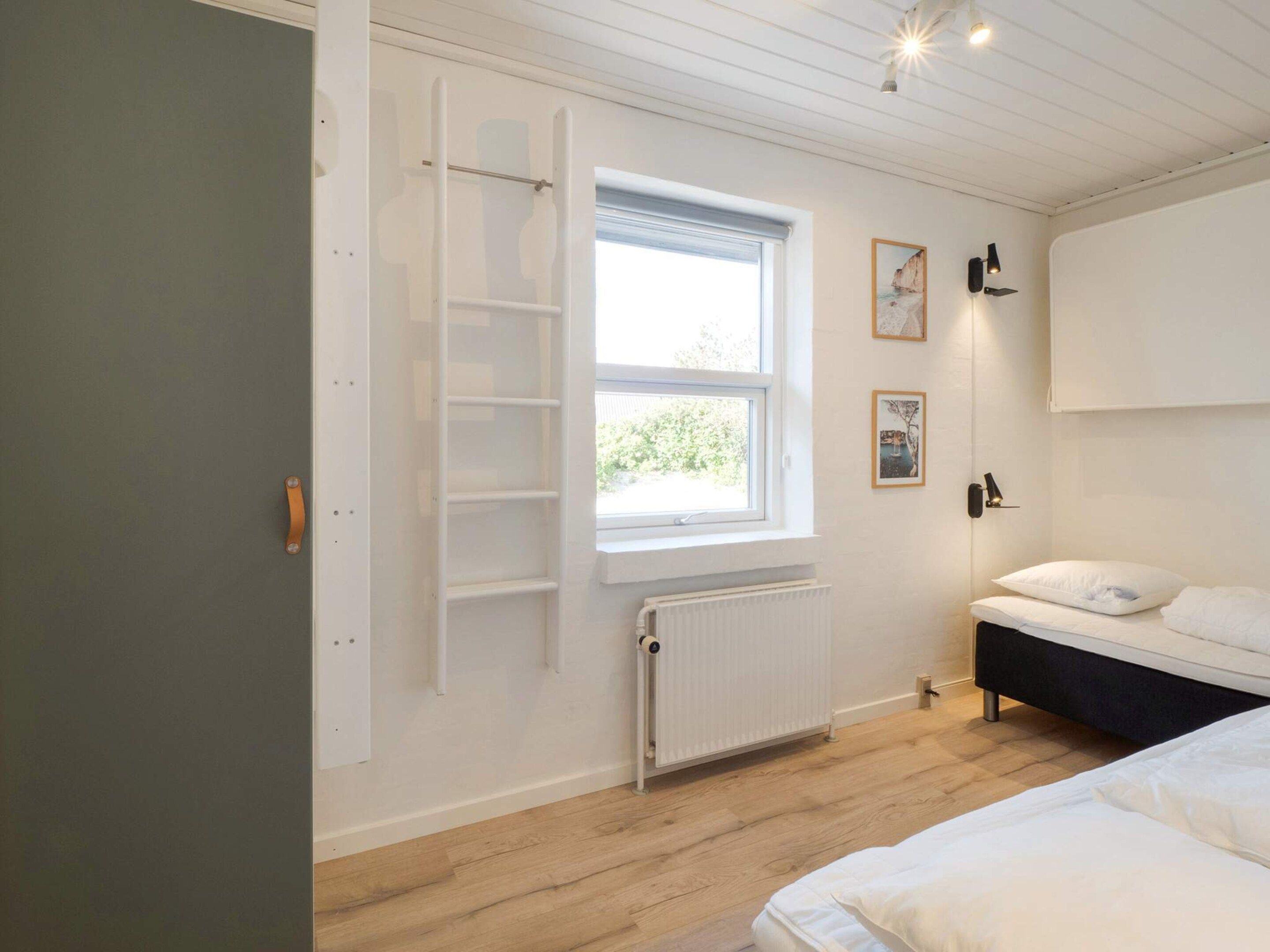 Un dormitorio con cama, ventana, radiador y puerta.