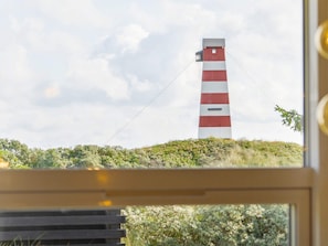 Et fyrtårn med et tårn i røde og hvide striber, set igennem et vindue med en træramme.
