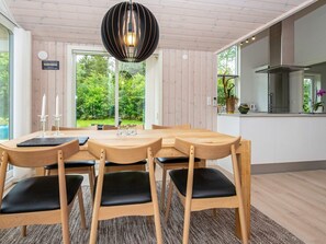 A modern kitchen with a large island, wooden chairs, and a hanging light fixture. - 6 Person Holiday Home in Oksbol (Oksbol)