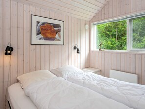 A bedroom with a bed, a window with a view of greenery, a framed picture on the wall, and two wall-mounted lamps. - 6 Person Holiday Home in Oksbol (Oksbol)