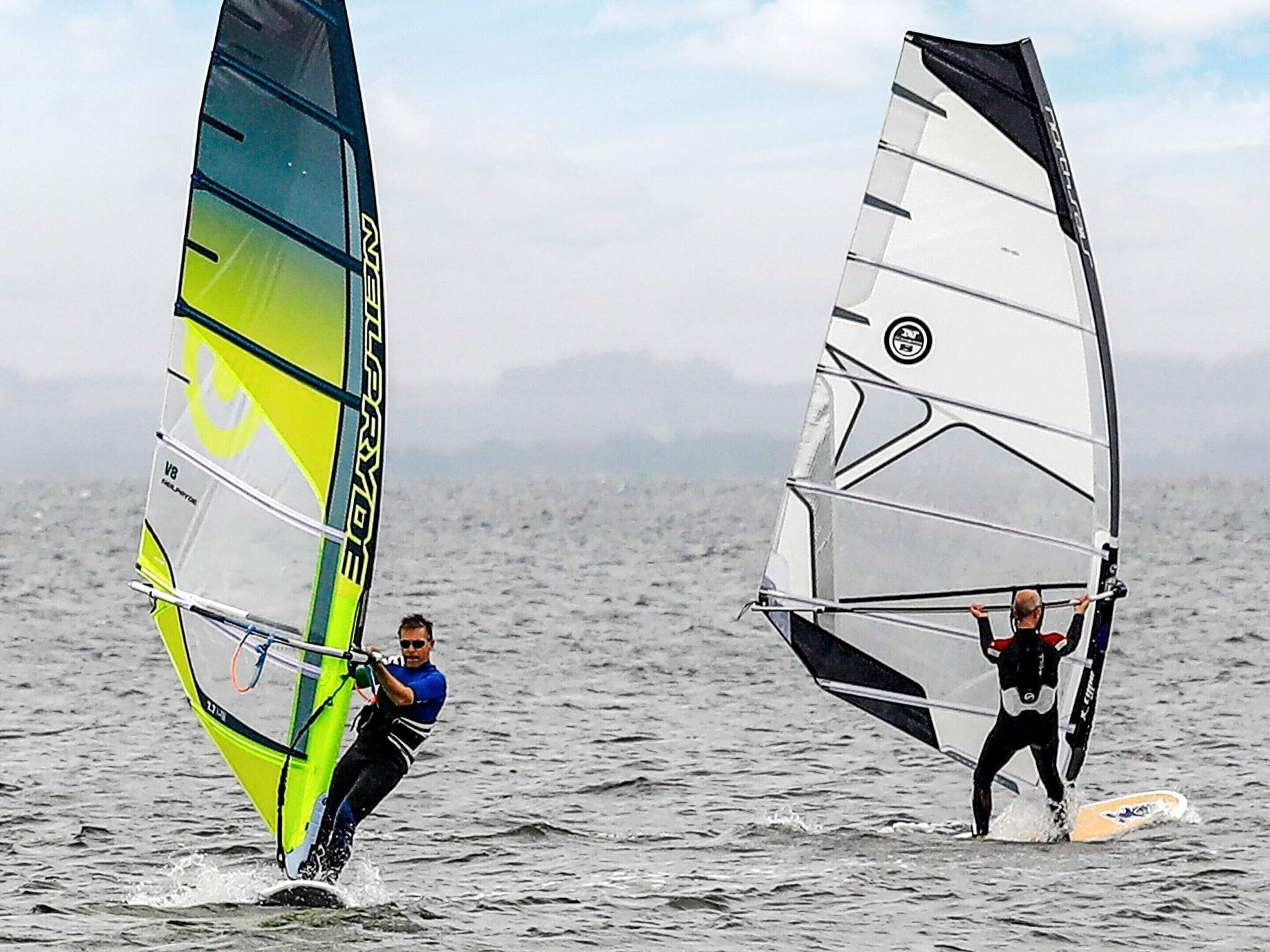 Zwei Personen Windsurfen auf dem Wasser.