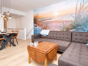 A living room with a large sofa, a wooden coffee table, and a dining area with a table and chairs.