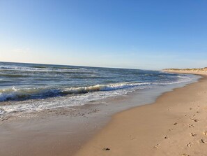 A beach with waves, a clear sky, and footprints on the sand.