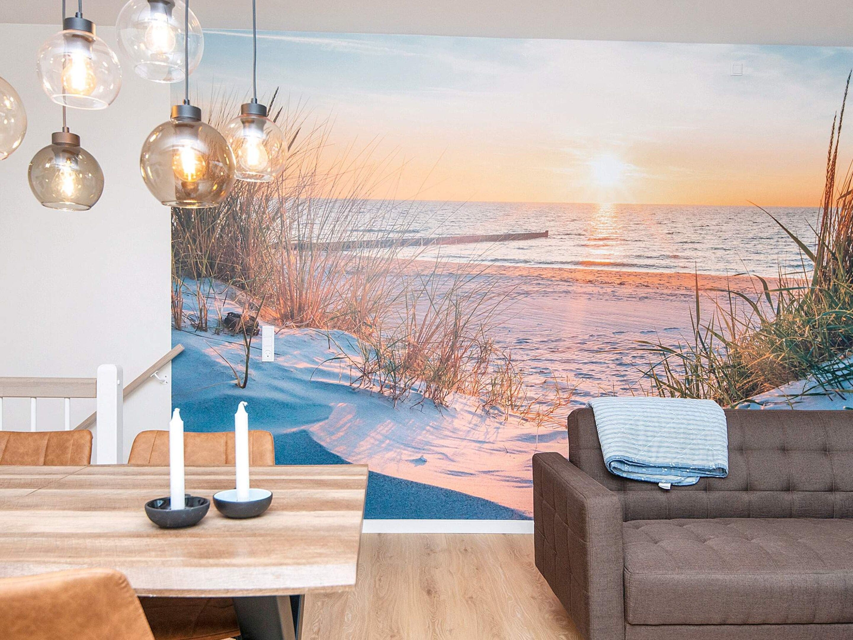 A room with a beach mural, a dining table with chairs, and a sofa.