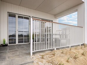 A modern building with a white exterior, large sliding glass doors, and a white metal fence.