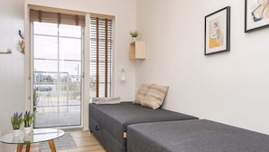 Una habitación moderna y minimalista con sofá cama, una mesita y una planta en maceta.