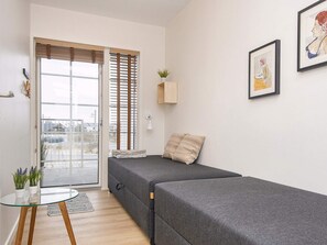 Una habitación moderna y minimalista con sofá cama, una mesita y una planta en maceta.