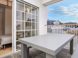 Un balcón con una mesa, una puerta corrediza de vidrio y vistas al vecindario.
