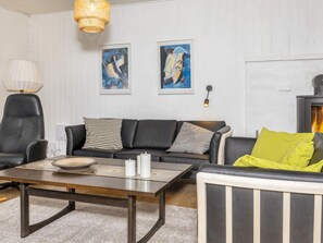 Un salon moderne avec un canapé, un fauteuil et une table basse. Deux tableaux abstraits encadrés sont accrochés au mur.