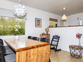 Una cocina moderna con una mesa de madera, sillas y una lámpara colgante.