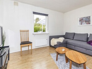 Un salon moderne avec un canapé gris, une chaise en bois, une petite table en bois et un radiateur.