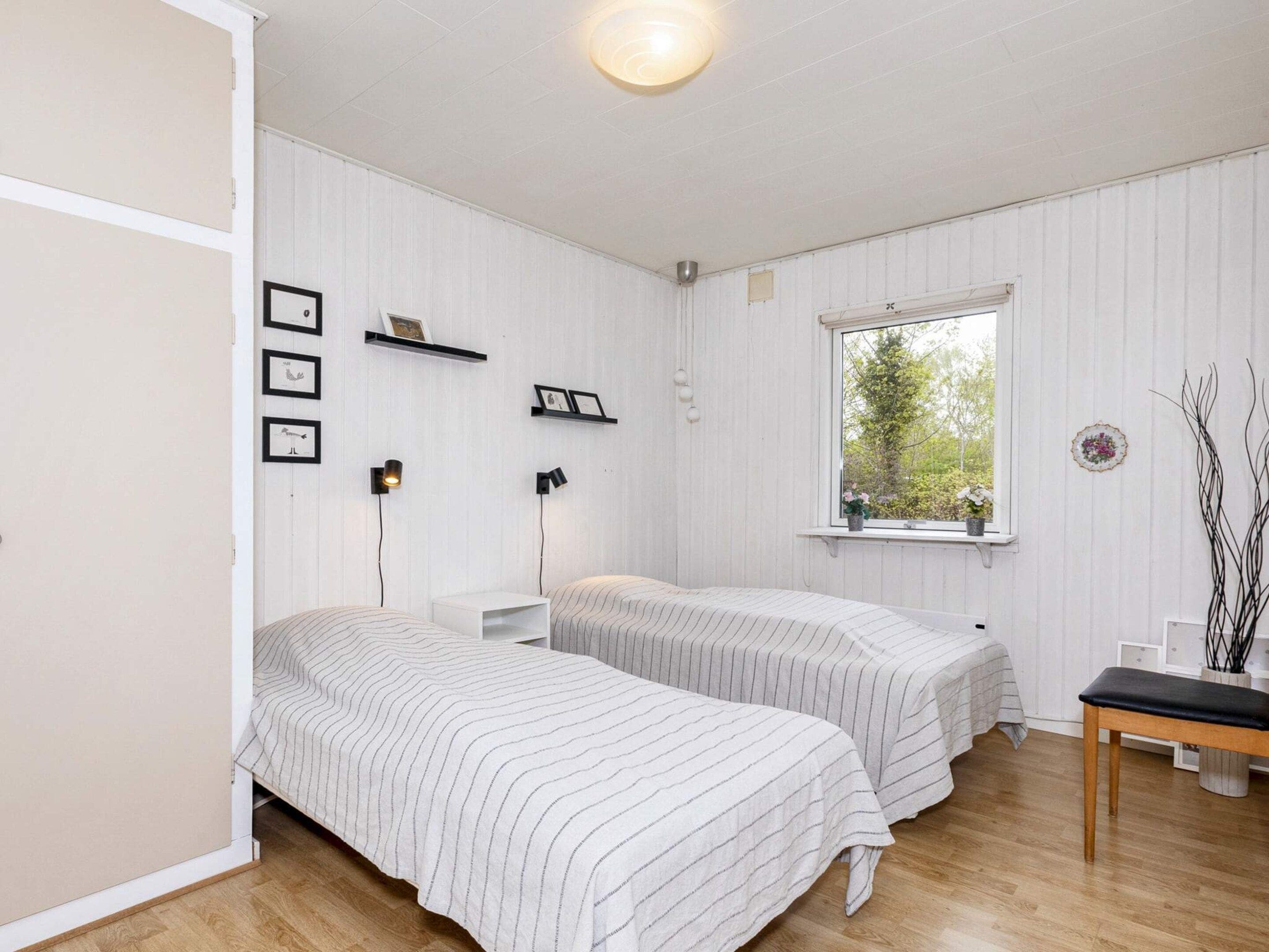 A room with two beds, a window, and a wooden floor.