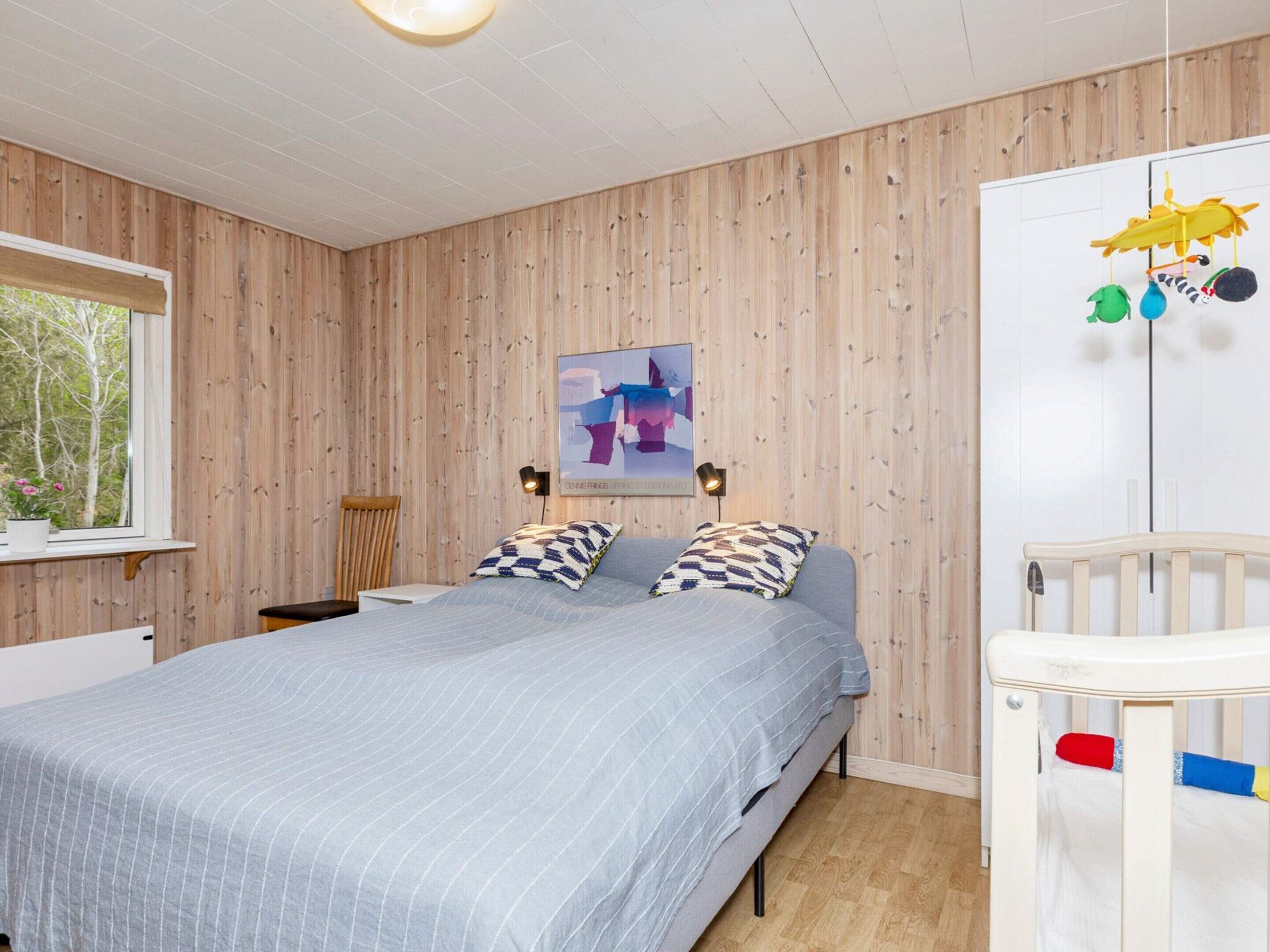 Ein Schlafzimmer mit einem Bett, einem Kinderbett, einem Fenster mit Aussicht und einem Wandbild.