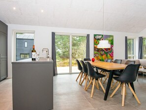 A modern kitchen with a dining area, large windows, and a colorful abstract painting.