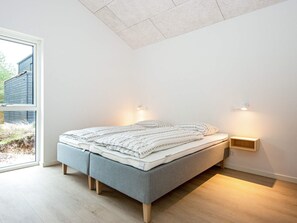 A modern bedroom with a bed, bedside lamps, and a view of the outdoors.