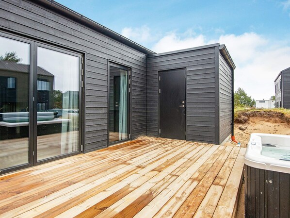 A modern house with a deck, sliding glass doors, and a hot tub.
