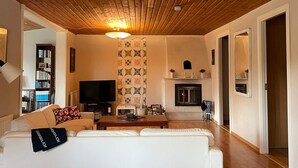 Un salon avec un plafond en bois, une cheminée, un téléviseur et un canapé.
