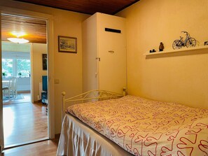 A bedroom with a single bed, a wardrobe, a small shelf with decorative items, and a door leading to a balcony. - 4 Person Holiday Home in Molltorp (Mölltorp)