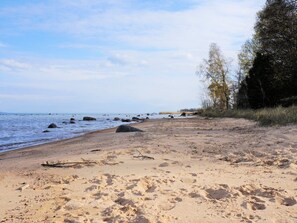 A sandy beach with scattered rocks and a calm sea. - 4 Person Holiday Home in Molltorp (Mölltorp)
