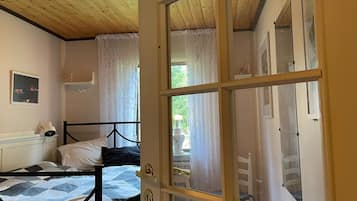 Una habitación con una cama, un ventanal con cortinas, una puerta y una lámpara en el techo.