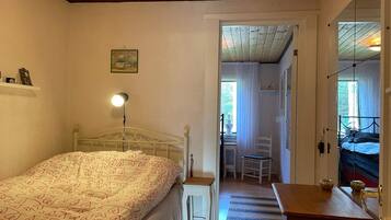 Un dormitorio con cama, lámpara de noche y vista hacia otra habitación.