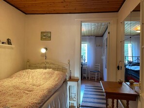 Une chambre à coucher avec un lit, une lampe de chevet et une vue sur une pièce adjacente.