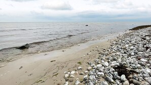 Een rotsachtig strand met kalm water en bewolkte lucht.