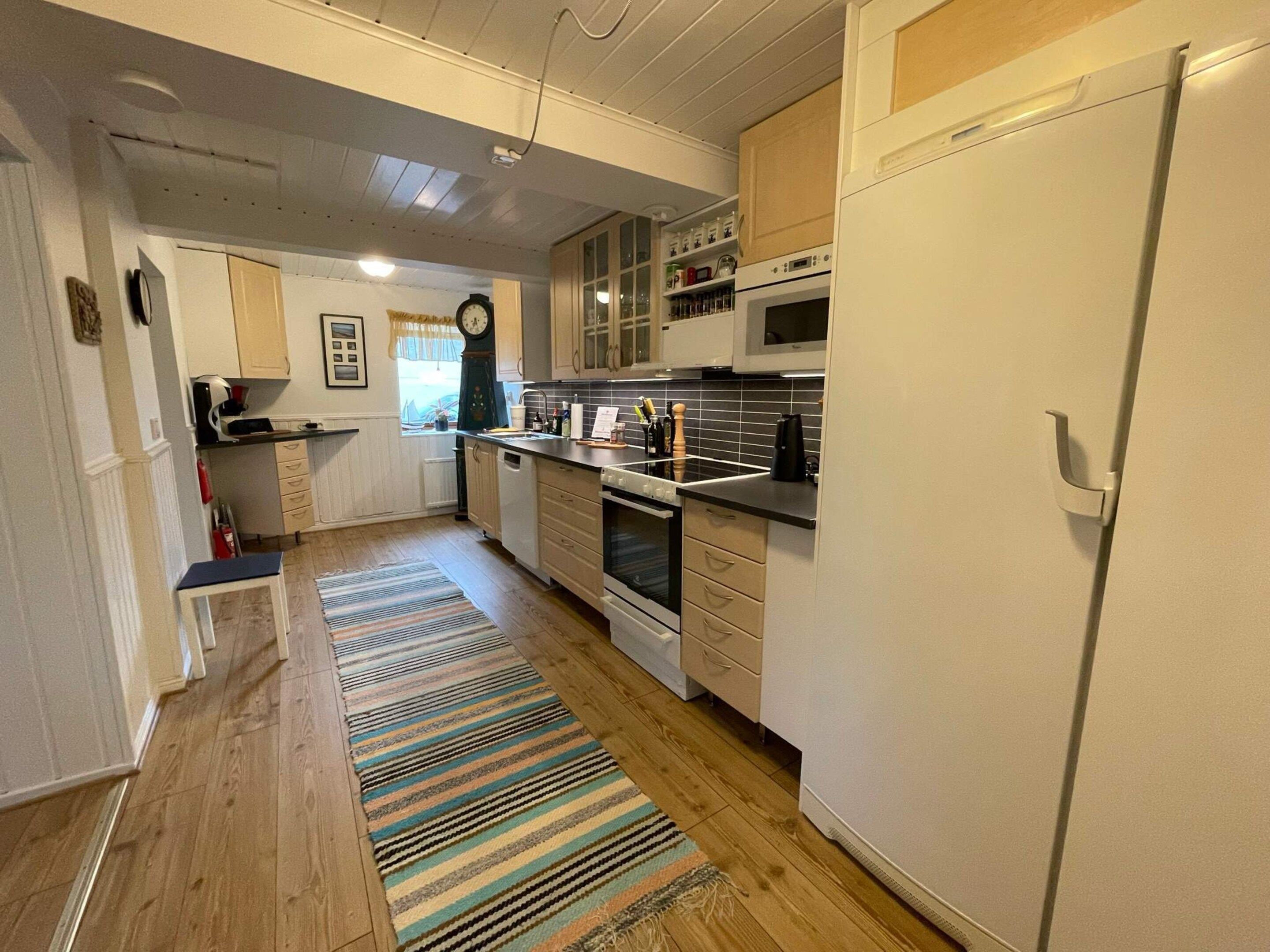 A kitchen with wooden cabinets, a microwave, an oven, and a refrigerator.