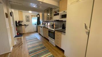 A kitchen with wooden cabinets, a microwave, an oven, and a refrigerator.