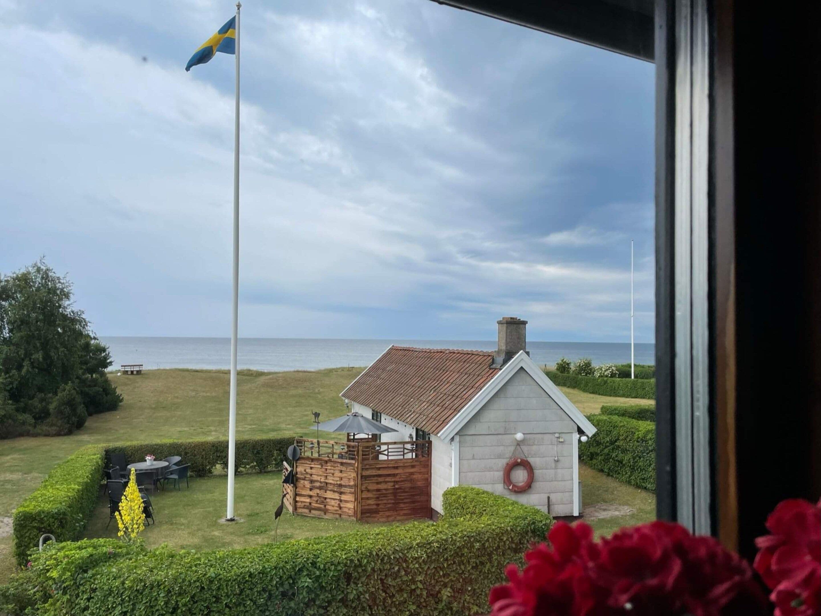 A coastal property with a small house, a flag, and a view of the sea.