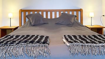 A bed with a wooden headboard, two pillows, and two bedside tables with lamps.