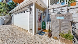 Una casa con puerta de garaje blanca, pared de piedra y terraza de madera.
