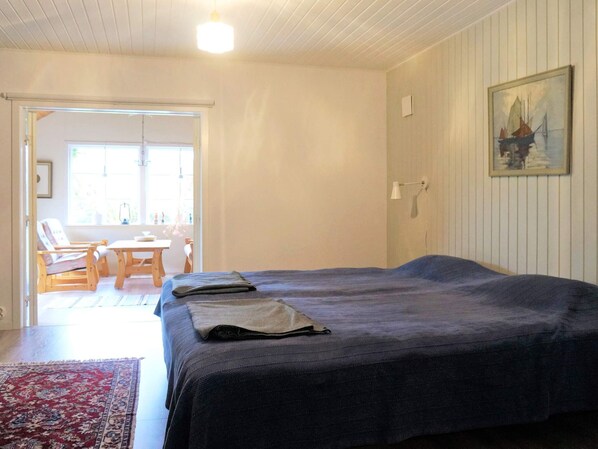 Une pièce comprenant un lit, une chaise, une table et un tableau accroché au mur.