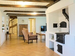 A spacious living area with a herringbone wood floor, a wooden chair, a television, and a fireplace.
