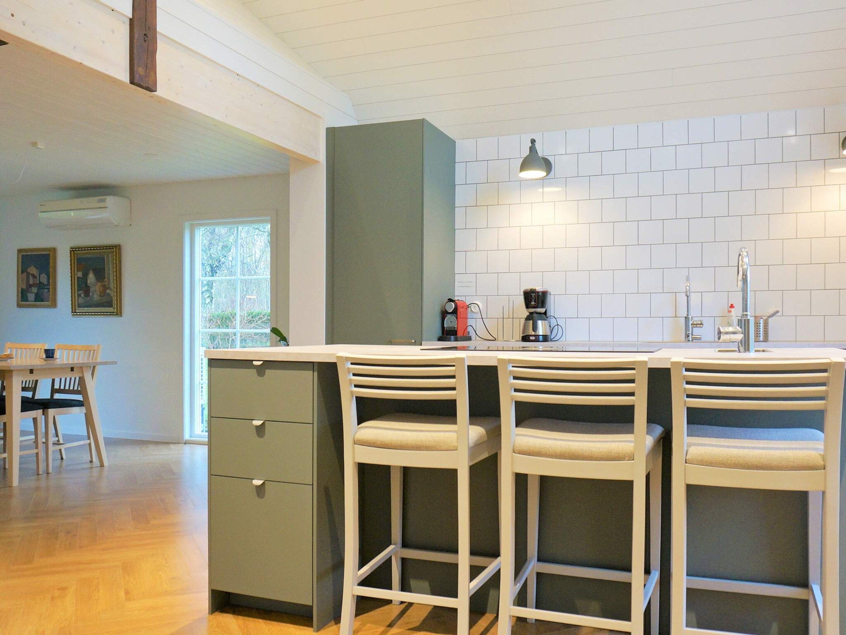 A kitchen with a bar area, a window, and a dining table with chairs.