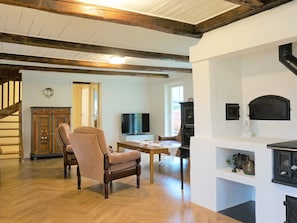 Uma sala de estar ampla com piso de madeira, lareira, televisão e área de jantar.