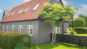 A two-story house with a red-tiled roof, multiple windows, and a tree in the front yard. - 5 Person Holiday Home in Knebel (Knebel)