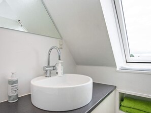 Bathroom features a sink, mirror, and window with a storage compartment.